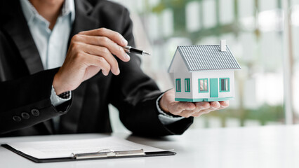 Real estate agents hold models of housing estates in projects to elaborate to clients, explaining and presenting information about homes and purchasing loans. Real estate trading concept.
