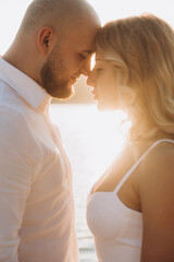 Wedding photosession at sunset of a beautiful couple, the bride in a white dress, and the groom in a white shirt and black trousers
