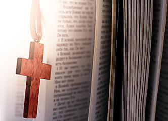 wooden cross and bible illuminated by bright warm light