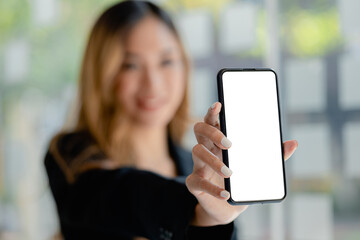 Asian woman holding white blank screen phone standing forward, smartphone blank screen for advertisement, smartphone application. Photo collage ideas for advertisements. copy space.
