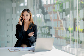 Asian woman talking on the phone, she is a salesperson in a startup company, she is calling customers to sell products and promotions. Concept of selling products through telephone channels.