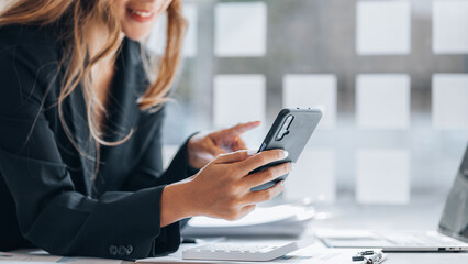 young businesswoman looking at financial information from a mobile phone, she is checking company financial documents, she is a female executive of a startup company. Concept of financial management.