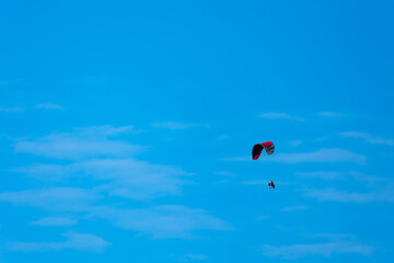 Patterned paraglide flying against the background of a blue sky. Photo taken in fine weather, late afternoon