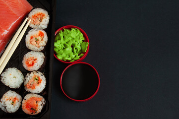 Set of sushi and maki with soy sauce over black stone background. Top view with copy space