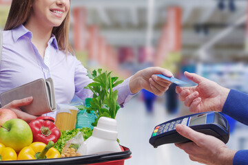 Woman paying for groceries using a credit card
