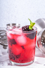 Refreshing summer infused fruit water. Iced lemonade with blackberry, ice cubes and mint. Red berry healthy mocktail or cocktail, on white background with bar utensils copy space