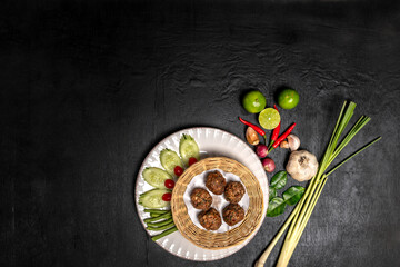 Fototapeta na wymiar Top view of Thai Traditional cuisine, Tasty Fried Pork or meat Balls with Garlic. Delicious recipe from Asia ingredients on a rustic dark black wooden table.Thailand restaurant food menu. Copy Space