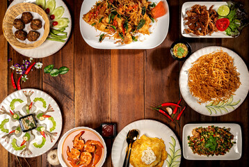 Top view on a delicious variety of Thai Traditional cuisine, Tasty Thai Food Mixed Selections Variety. A Delicious recipe from Asia ingredients on dark wooden table. Restaurant food menu. Copy Space