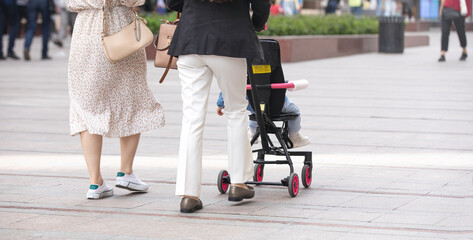 Mother walking in city baby in stroller.