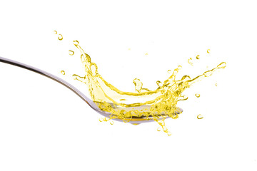 Cooking oil splashing on stainless spoon isolated on white background.