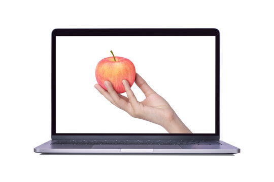 Hand hold pink fuji apple on laptop computer screen isolated on white background. (My image)