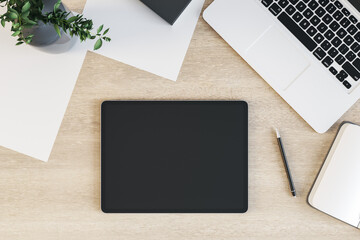 Tablet with blank screen is on top of wooden office desk table with laptop computer and supplies, above view. Mock up, 3D Rendering.