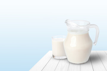 Jug and glass of fresh milk on white wooden table with blue background. Copy space.
