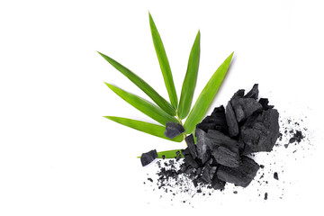 Broken activated charcoal with bamboo leaf isolated on white background. Top view.