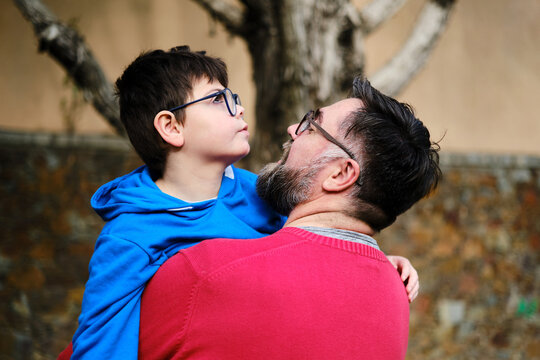 Man holding and hugging his disabled son while they enjoy time together outdoors.