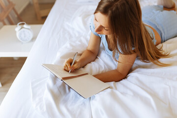 Mental health care, positive thinking and wellness concept. Woman lying in bed, practicing stress relief challenge with journal about feeling and gratitude list, focus on word mental.