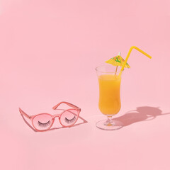 Summer creative layout with pink eyeglasses with false eyelashes and cocktail on pastel pink background. 80s or 90s retro fashion aesthetic fun concept. Minimal summer holiday idea.