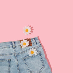 Spring creative layout with faded jeans and white flowers on pastel pink background. 80s or 90s...