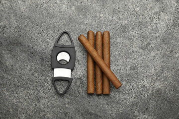 Cigars and guillotine cutter on grey table, flat lay