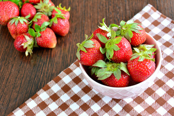 fresh garden strawberries in bowl on tablecloth, close-up