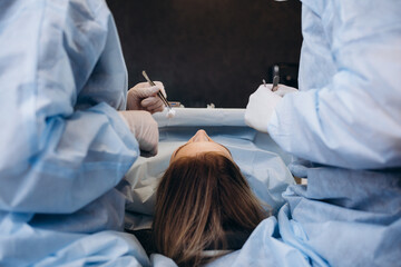 Surgeon and his assistant performing cosmetic surgery on nose in hospital operating room. Nose...