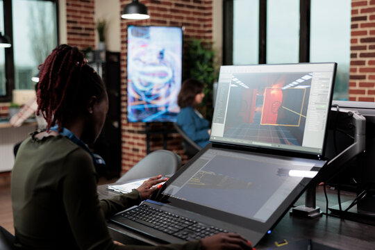 Digital artist sitting at desk, using PC to design game environment and levels. Development department creator employee working with CGI in order to achieve virtual realism.