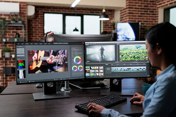 Creative company professional movie footage editor sitting at multi monitor workstation while editing film frames. Expert videographer improving video quality using specialized software. - obrazy, fototapety, plakaty