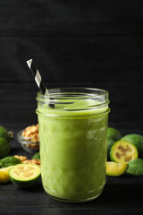 Fresh feijoa smoothie in glass on black wooden table, closeup