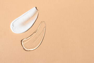 Texture samples of cosmetic products for body care. Transparent liquid body gel and cleansing cream, smears on a beige background with copy space.