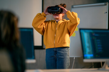 Schoolgirl wearing virtual reality goggles at school in computer science class