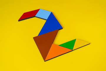 Colorful number 2 made with tangram toy, colored tangram number two isolated on yellow background, kids game idea, teaching counting for children, puzzle toy, side view of second numeric