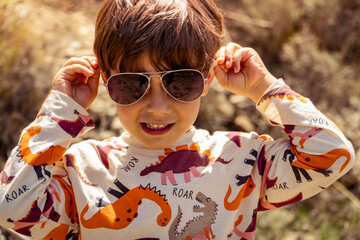 boy putting on purple sunglasses in summer