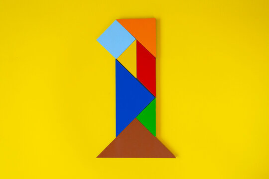 Colorful number 1 made with tangram toy, colored tangram number one isolated on yellow background, kids game idea, teaching counting for children, puzzle toy, top view of first numeric