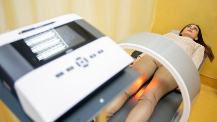 Magnet therapy system. Patient on a treatment bed with Magnetic Field Therapy on her leg. Medicine...