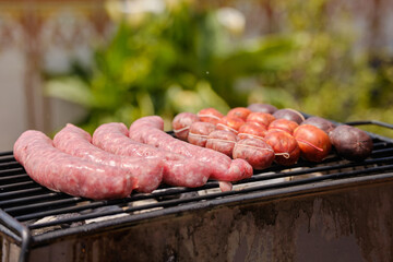 Man cooking botifarra sausage and black pudding on the barbecue grill for an outdoor summer party. Barbecue smoke. Background of food.