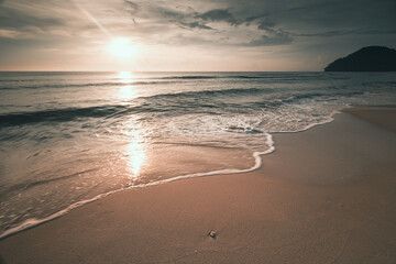long exposure shot soft wave of the sea on the sandy beach at morning sunlight .