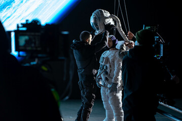 Behind the scenes - Caucasian female stuntwoman wearing a spacesuit being prepared for the shot