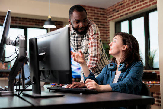 Smiling coworker talking with friendly 3D artist about electronic arts and digital graphics developing. Creative agency diverse employees in brainstorming production ideas.