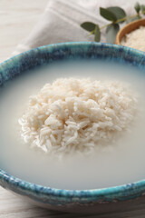 Bowl with rice soaked in water on table, closeup