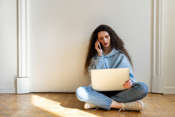 Portrait of a successful young european business woman or freelancer using a laptop, standing on the floor or in a coworking space, looking away, dreaming, thinking about starting a new startup