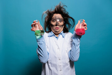Mad chemist with dirty face and messy hair having flasks filled with unknown chemical substances....