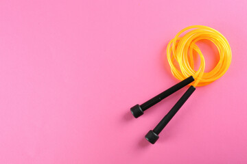 Skipping rope on pink background, top view. Space for text