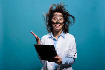 Crazy scientist with dirty face and messy hairstyle having touchscreen tablet acting shocked and mad after failed experiment explosion. Wacky looking chemist being baffled after lab discovery. - obrazy, fototapety, plakaty