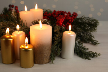 Fototapeta na wymiar Different burning candles and Christmas decor on white wooden table