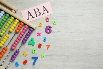 Paper sheet with abbreviation ABA (Applied behavior analysis), abacus and colorful numbers on white wooden table, flat lay. Space for text - obrazy, fototapety, plakaty