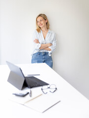 portrait of pretty young blonde business woman standing by her ergonomic height adjustable work desk in her home office