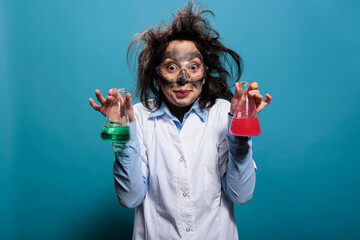 Crazy chemist holding glass flasks filled with toxic chemical compounds after laboratory explosion. Mad wacky lab worker having beakers filled with liquid substances after failed laboratory experiment