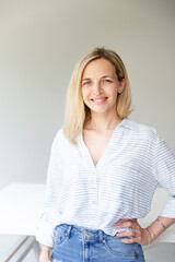 Naklejka premium portrait of pretty young blonde business woman standing by her ergonomic height adjustable work desk in her home office