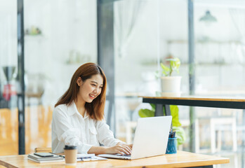 Portrait of Asian young female working on laptop and financial report at office. © PaeGAG
