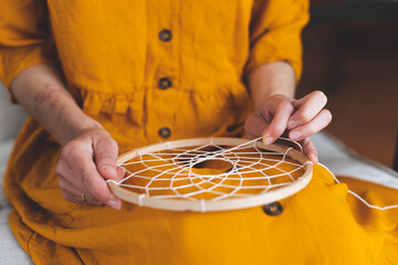 Woman making a dream catcher from threads - obrazy, fototapety, plakaty